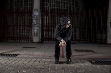 sad woman alone on street suffering depression desperate and helpless wearing hoodie