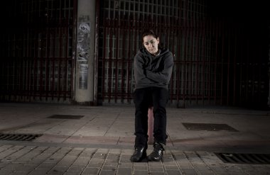 sad woman alone on street suffering depression desperate and helpless wearing hoodie