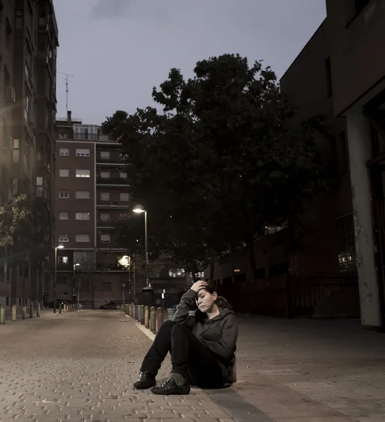 Молодая грустная женщина, сидящая на улице ночью в одиночестве — стоковое фото
