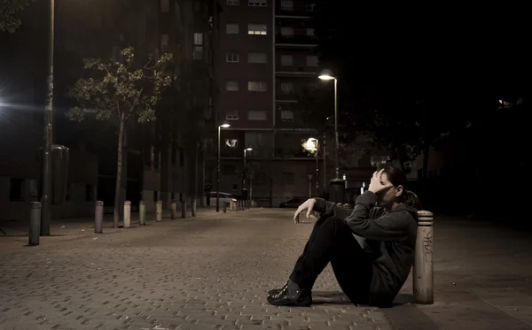 Young sad woman sitting on street ground at night alone desperate suffering depression left abandoned — Stok fotoğraf