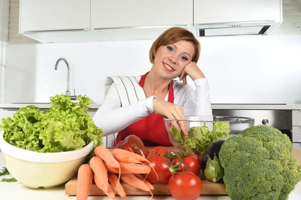 Giovane bella donna in grembiule rosso a casa cucina preparare insalata di verdure ciotola sorridente felice — Foto Stock