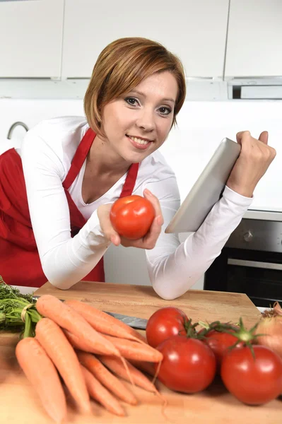 Felice casa cuoco donna in grembiule in cucina utilizzando tablet digitale come libro di cucina — Foto Stock