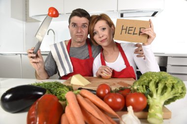 American couple in stress at home kitchen in cooking apron asking for help frustrated clipart