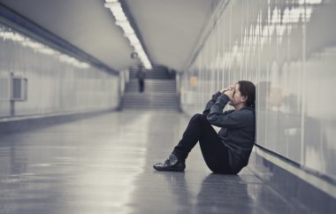 young sad woman in pain alone and depressed at urban subway tunn