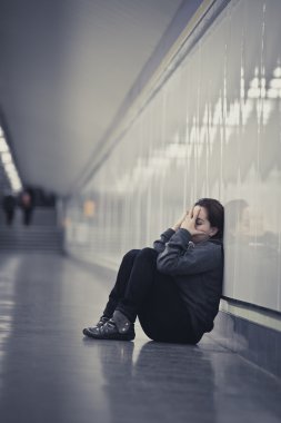 young sad woman in pain alone and depressed at urban subway tunn