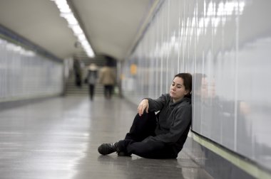 young sad woman in pain alone and depressed at urban subway tunnel ground worried suffering depression