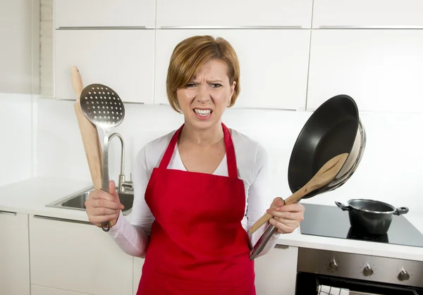 Casa cozinheiro mulher em avental vermelho na cozinha doméstica segurando panela e casa em estresse — Fotografia de Stock