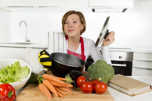 Casa cozinheiro mulher em avental vermelho na cozinha doméstica segurando panela de cozinha com sopa quente ensopado vegetal cheiroso — Fotografia de Stock