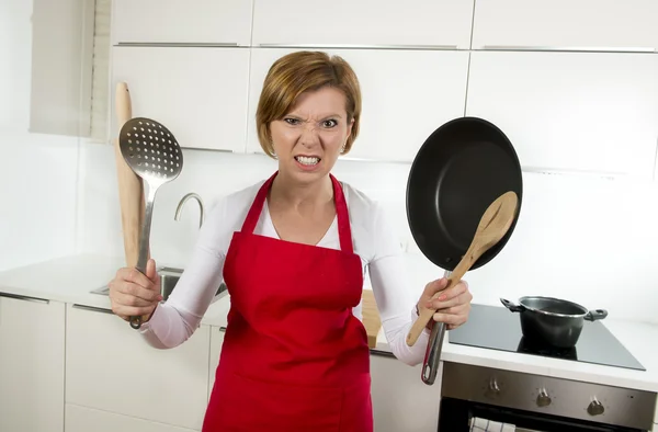 Gotować w domu kobieta w czerwonym fartuch w domowej kuchni posiadania patelni i gospodarstwa domowego w stres — Zdjęcie stockowe
