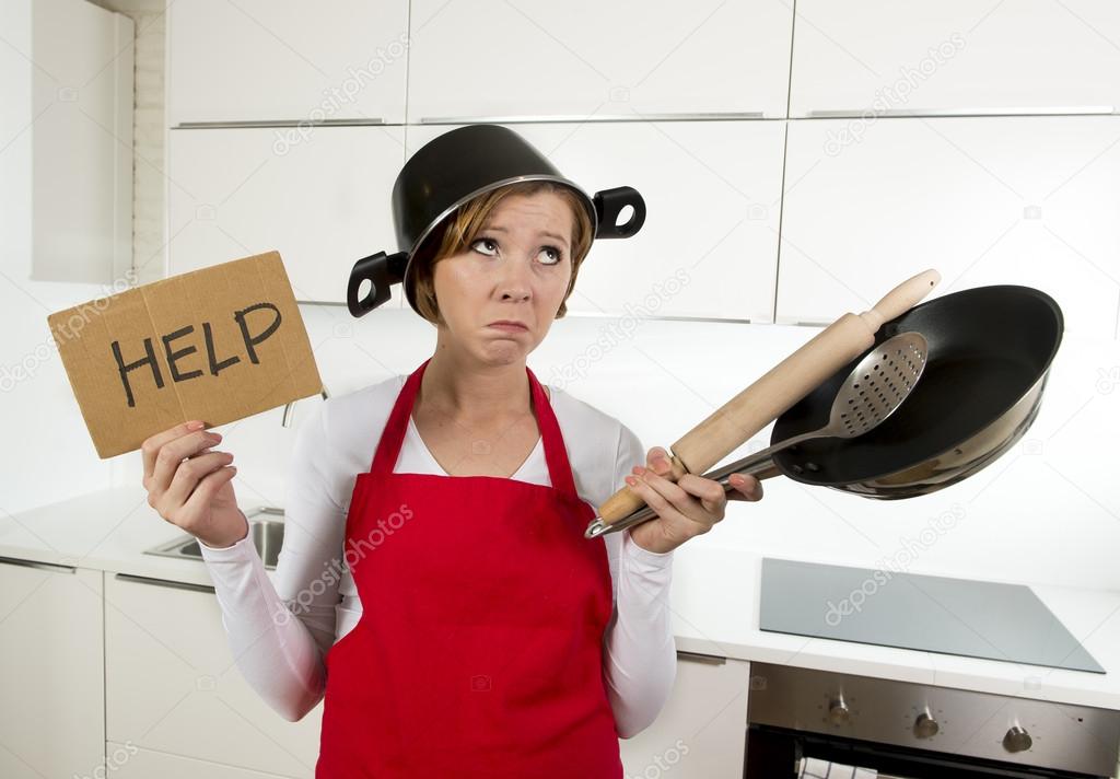 young attractive home cook woman in red apron at  kitchen holding pan and household with pot on her head in stress