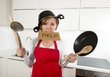 young attractive home cook woman in red apron at  kitchen holding pan and household with pot on her head in stress clipart