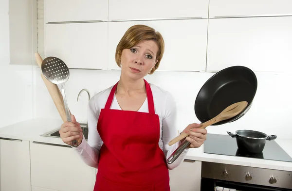 Hausfrau in roter Schürze in der heimischen Küche mit Pfanne und Haushalt im Stress — Stockfoto