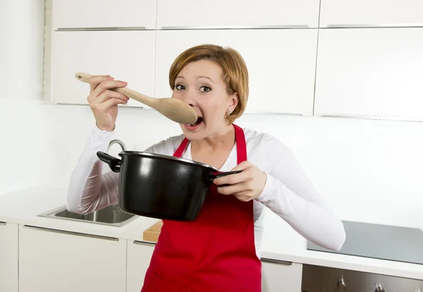 Bela casa cozinheiro mulher na cozinha segurando colher e panela de cozinha saboreando sopa deliciosa — Fotografia de Stock