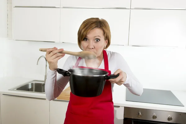 Beautiful home cook woman at kitchen holding spoon and cooking pot — Stockfoto