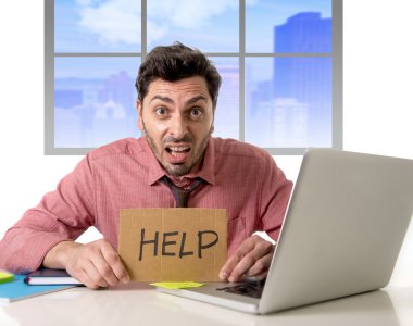 sad businessman at office desk working on computer laptop asking for help depressed