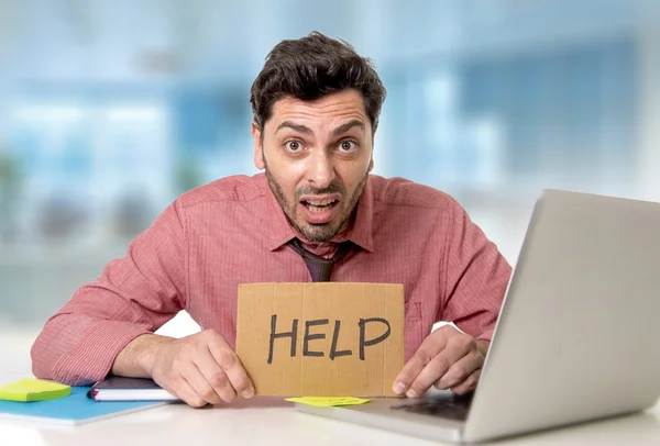 Geschäftsmann am Schreibtisch, der am Computer-Laptop arbeitet und um Hilfe bittet, hält Pappschild traurig in der Hand — Stockfoto