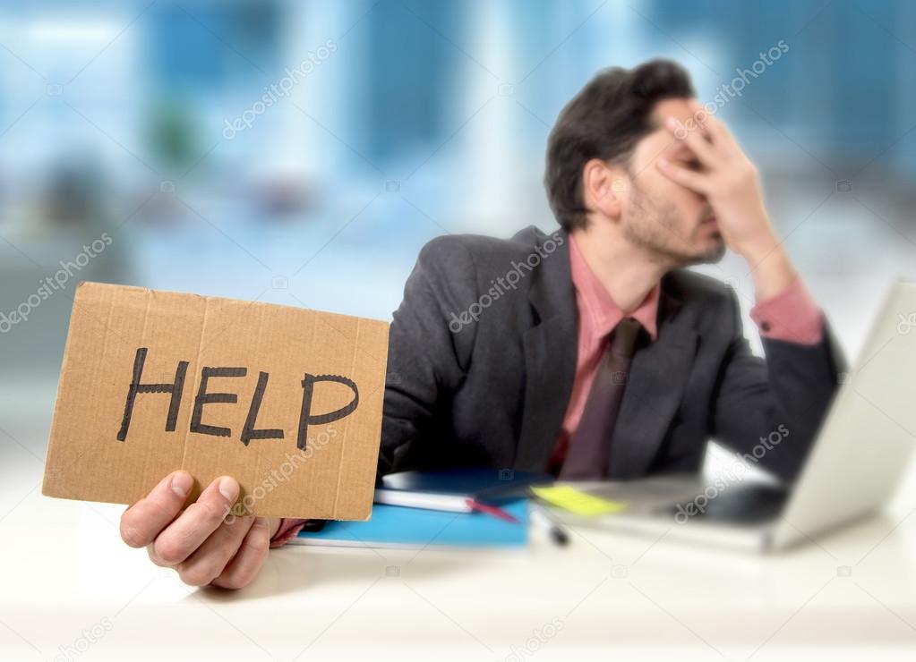 sad businessman at office desk working on computer laptop asking for help depressed