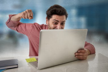 businessman sitting at office desk working stressed on computer laptop overworked throwing punch in work stress