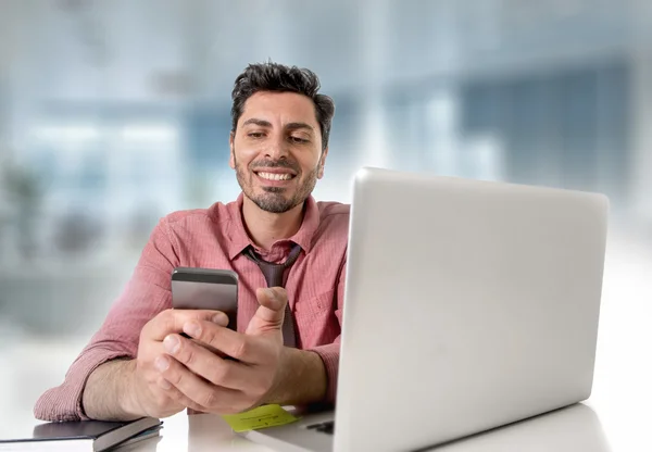 Homem de negócios atraente feliz trabalhando na mesa de escritório usando telefone celular — Fotografia de Stock