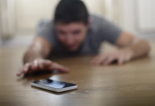 Man trying to reach mobile phone creeping on the ground in smart phone and internet addiction concept — Stok fotoğraf