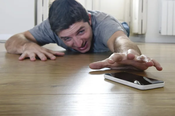 Homem tentando alcançar o telefone móvel rastejando no chão no conceito de vício em telefone inteligente e internet — Fotografia de Stock