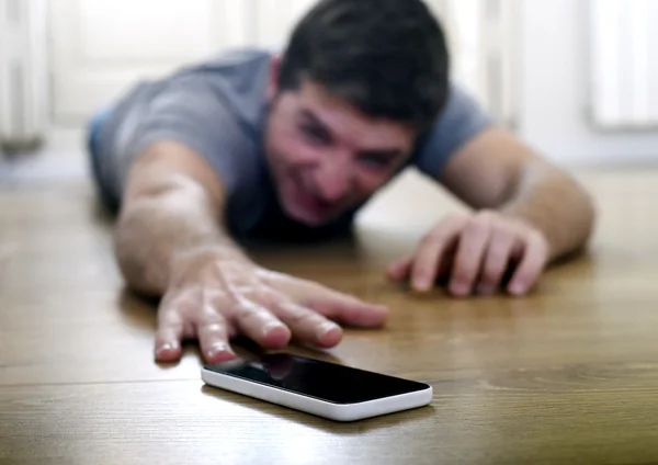 Man trying to reach mobile phone creeping on the ground in smart phone and internet addiction concept — Stock fotografie