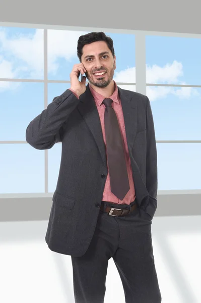 Unternehmensporträt eines jungen attraktiven Geschäftsmannes im Büro per Handy — Stockfoto