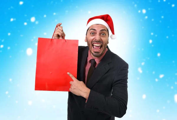 Funny businessman in Christmas Santa hat holding red shopping ba — Stock Photo, Image