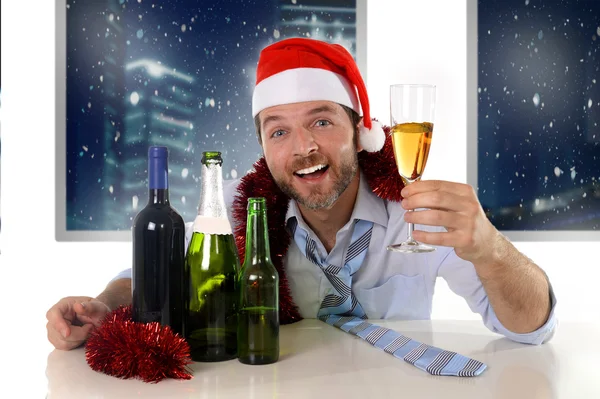 Пьяный счастливый бизнесмен в Санта-шляпе с бутылками алкоголя в новогоднем тосте с бокалом шампанского — стоковое фото
