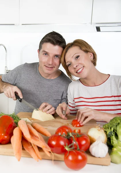 Young American couple working at home kitchen preparing vegetable salad together smiling happy — Stockfoto