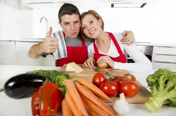 Junges schönes Paar arbeitet in der heimischen Küche und bereitet gemeinsam Gemüsesalat zu und lächelt glücklich — Stockfoto