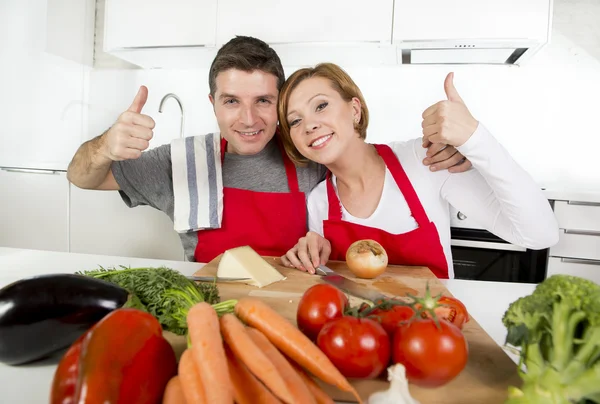 Junges schönes Paar arbeitet in der heimischen Küche und bereitet gemeinsam Gemüsesalat zu und lächelt glücklich — Stockfoto