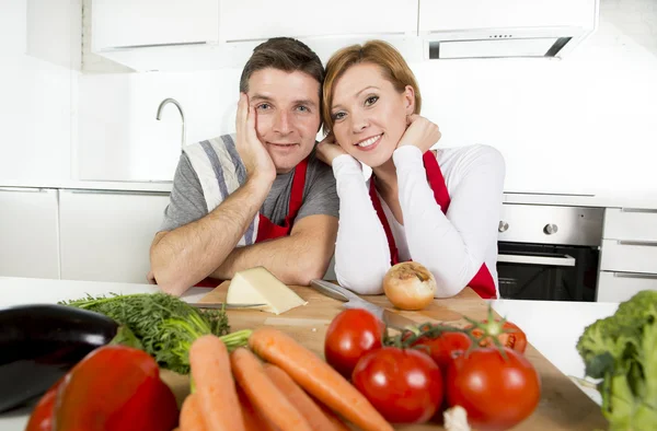Junges schönes Paar arbeitet in der heimischen Küche und bereitet gemeinsam Gemüsesalat zu und lächelt glücklich — Stockfoto