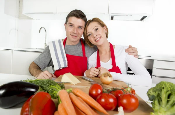 Joven hermosa pareja trabajando en casa cocina preparando ensalada de verduras juntos sonriendo feliz —  Fotos de Stock
