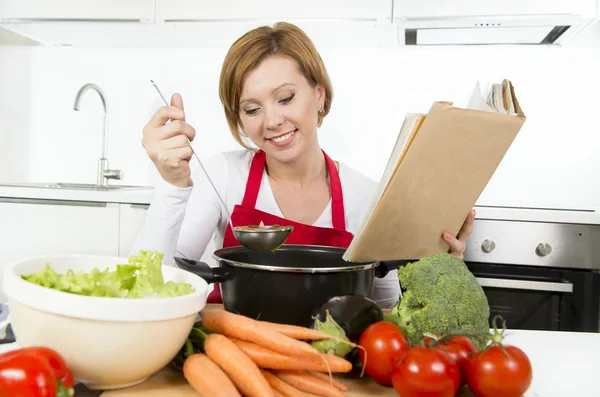 Привлекательный повар женщина готовит овощной тушеный суп читать рецепт поваренная книга на домашней кухне — стоковое фото