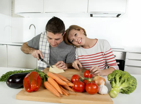 Young American couple working at home kitchen preparing vegetable salad together smiling happy — Stockfoto