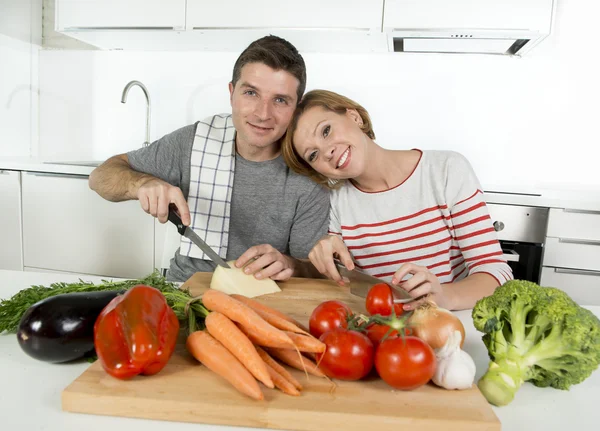 Young American couple working at home kitchen preparing vegetable salad together smiling happy — Stockfoto