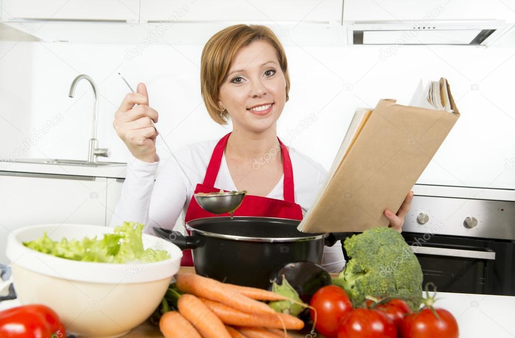 attractive cook woman preparing vegetable stew soup reading recipe cookbook at domestic kitchen 