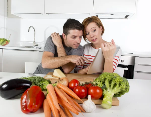 Ζευγάρι Αμερικανών στην εγχώρια κουζίνα σύζυγος μετά από συνταγή σε ψηφιακή μαξιλάρι εργασίας μαζί με το σύζυγό της — Φωτογραφία Αρχείου