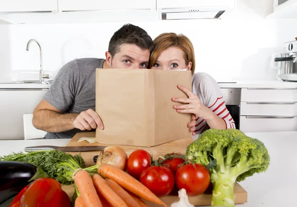 Casal americano trabalhando na cozinha doméstica seguinte receita leitura livro de receitas juntos — Fotografia de Stock