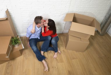 happy American couple sitting on floor kissing celebrating movin