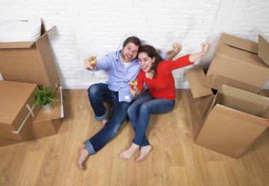 happy American couple sitting on floor unpacking together celebr