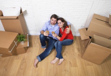 happy American couple sitting on floor unpacking together celebr