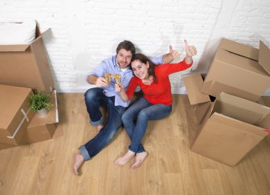 happy American couple sitting on floor unpacking together celebr