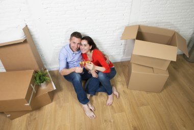 happy American couple sitting on floor unpacking together celebr
