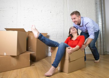 happy American couple unpacking moving in new house playing with
