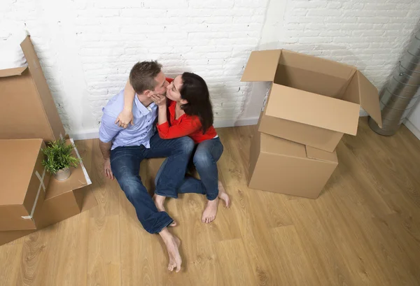 Happy American couple sitting on floor kissing celebrating movin — Stockfoto