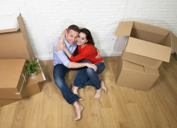 Happy American couple sitting on floor kissing celebrating movin — Stockfoto