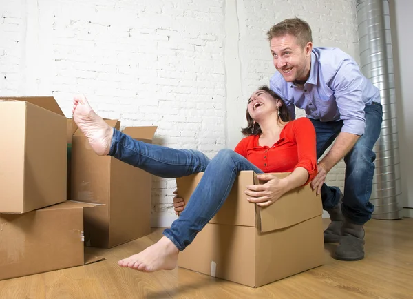 Happy American couple unpacking moving in new house playing with — Stockfoto