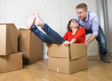 happy American couple unpacking moving in new house playing with